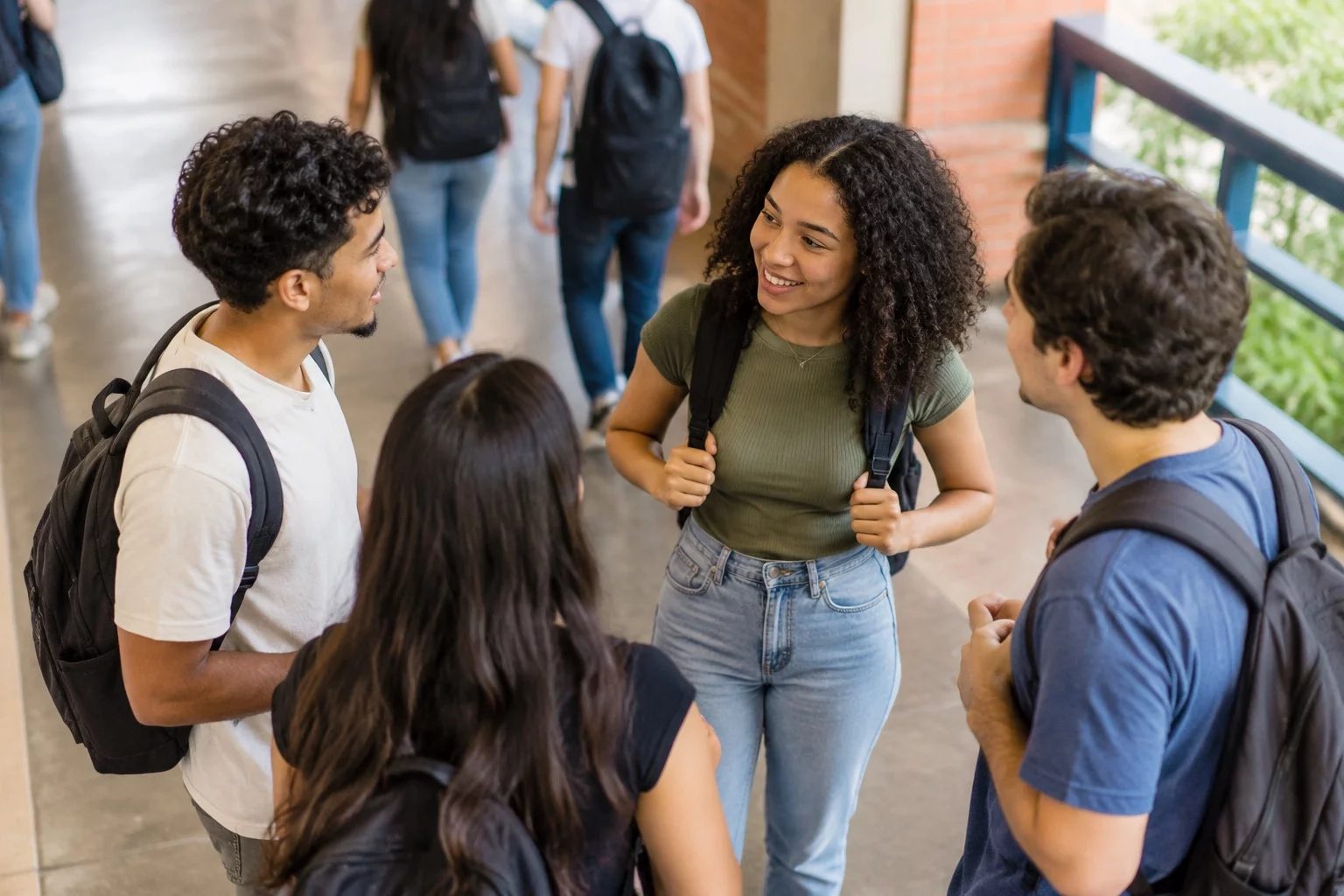 Estudantes com mochilas conversando no corredor de uma universidade
