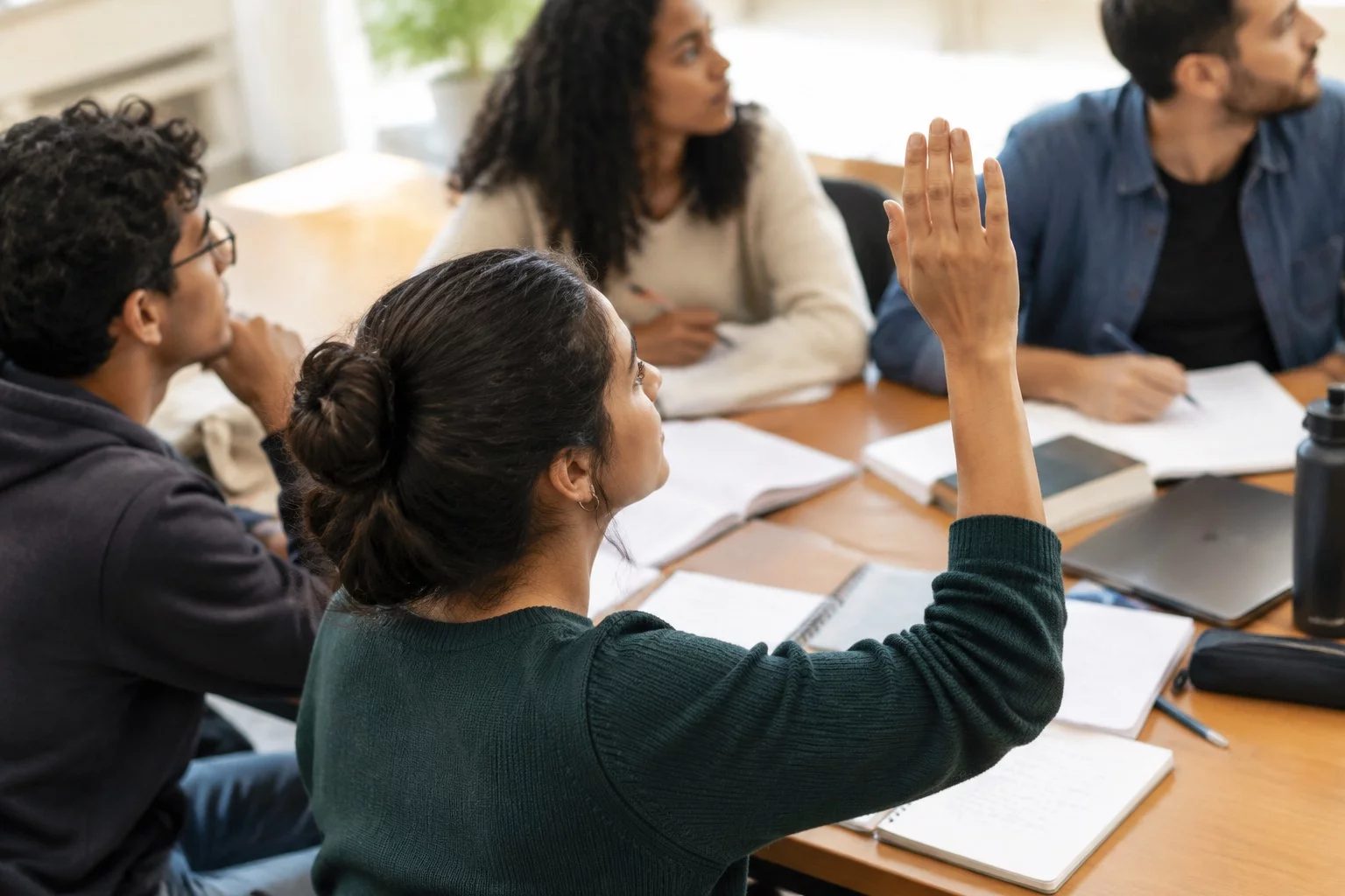 Estudante levantando a mão em uma mesa de seminário coberta de anotações